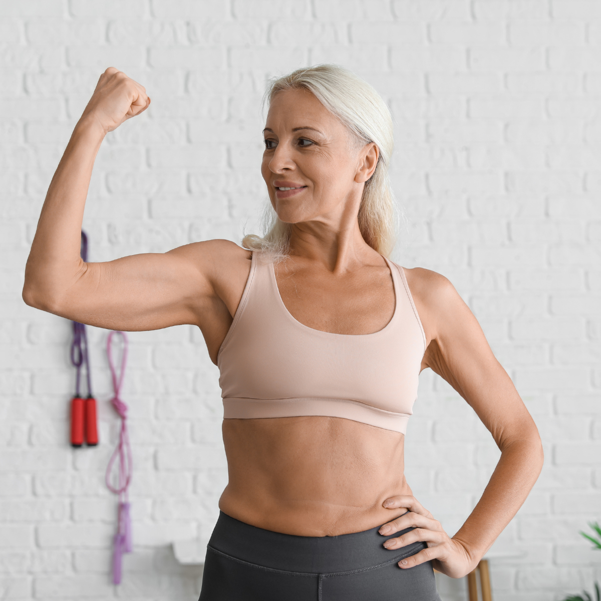 Woman in gym gear lifting arm and showing bicep muscle
