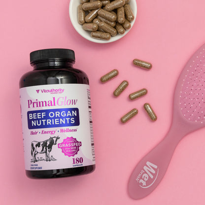 Primal Glow Beef Organ Nutrients Bottle on pink background and capsules